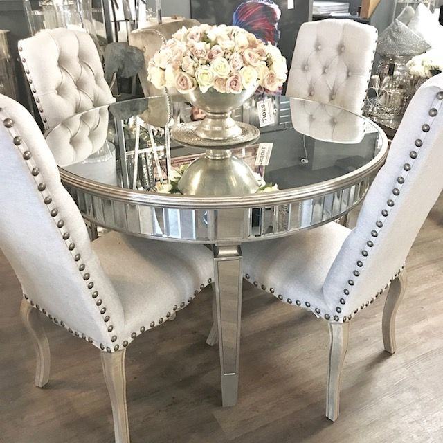 Wooden chairs at table with tableware in dining room interior with lamps  and round mirror