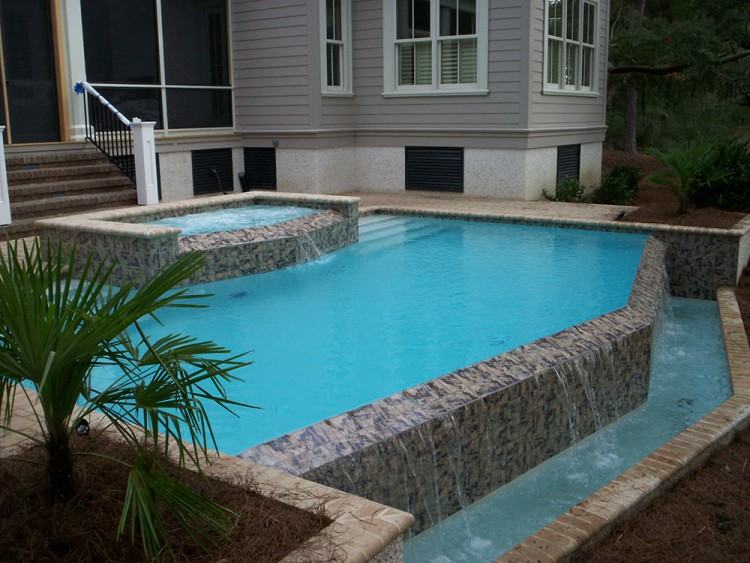 The luminous space is cantilevered over a stream and enclosed in glass on  three sides; at the end of the pool, the glass extends below