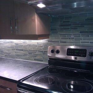 Back painted glass panels add a pop of teal to this loft kitchen in New  Jersey