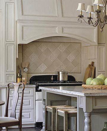 Beautiful kitchen features a stainless steel French kitchen hood stands  over a white Moroccan tiled backsplash as well as a Wolf dual range